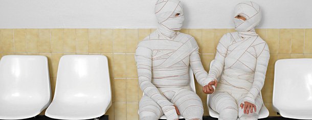 Mr und Ms right sitzen sich vermummt und eingewickelt in Verbandsmaterialnebeneinander