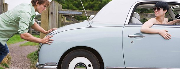 Mann zeigt Manieren in der Liebe und schiebt Auto an während Frau im Auto sitzt und den Wagen anfährt
