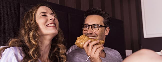Frau und Mann mit unterschiedlichen Beziehungspersönlichkeiten beim Frühstück im Bett