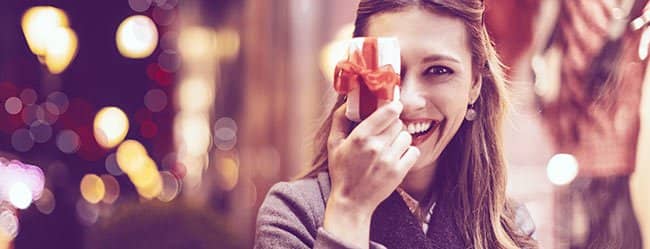 Frau hält sich Geschenk vor die Augen als Symobl für Geschenke für Frauen