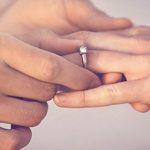 Mann macht Frau einen Heiratsantrag und steckt einen Verlobungsring an ihren Finger
