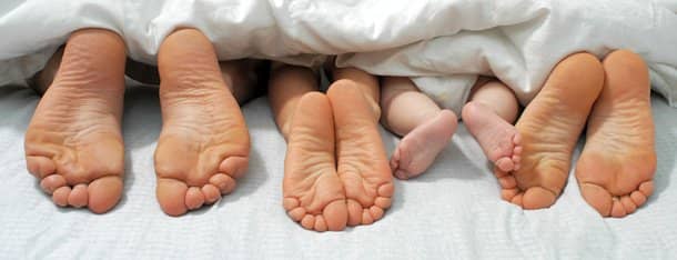 Eltern und Kinder Füße unter der Decke als Symbol für Kuckuckskind