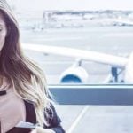 Frau steht am Flughafen mit Handy um falschen Mann zu erkennen
