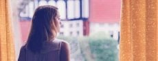 Frau schaut aus dem Fenster als Symbol für emotionale Abhängigkeit