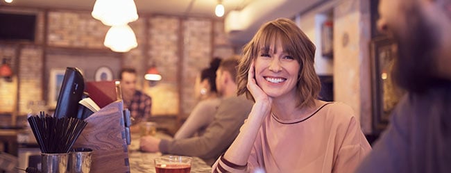 Frau flirtet lächelnd in einer Bar