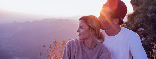 Mann und Frau genießen die romantische Idee im Freien und schauen dem Sonnenuntergang entgegen