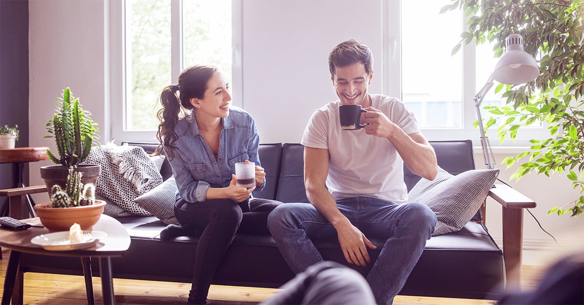 Ein Mann und eine Frau sitzen mit einem Kaffee auf dem Sofa