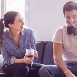 Ein Paar trinkt zu Hause einen Kaffee, er schaut unsicher zu Boden
