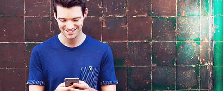 Mann schaut auf sein Smartphone und freut sich über eine Antwort