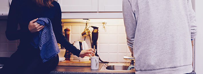 Ein Paar bei der Hausarbeit in der Küche – sie teilen sich die Aufgaben