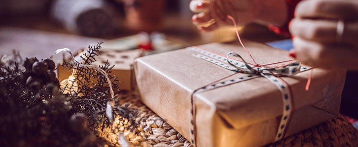 Geschenke liegen zwischen Lichterketten und Tannenzweigen