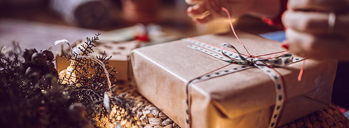 Geschenke liegen zwischen Lichterketten und Tannenzweigen