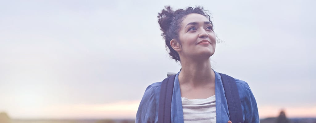 Eine Frau vor blauem Himmel, die in die Ferne blickt. Sie ist Single, die Gründe dafür sind vielfältig.