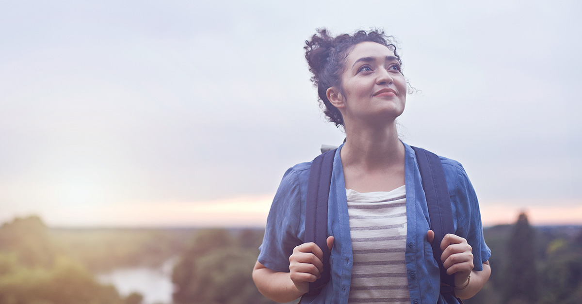 Eine Frau vor blauem Himmel, die in die Ferne blickt. Sie ist Single, die Gründe dafür sind vielfältig.