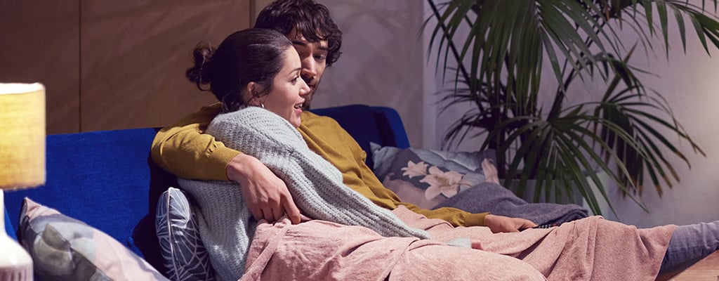 Ein Paar liegt gemeinsam auf dem Sofa, ein Symbol für Bindungserfahrungen in Beziehungen.