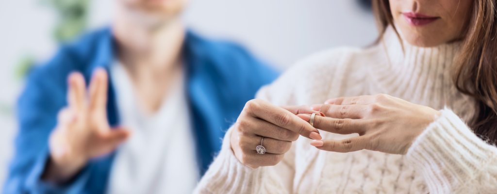 Eine Frau streift ihren Ehering vom Finger.